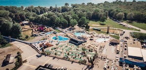 Luchtbeeld van een resort met een zwembad, glijbanen en een golfbaan.