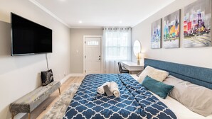 Un dormitorio moderno con una cama grande, un escritorio y un televisor.