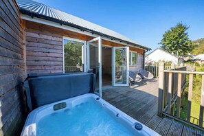 En træhytte med jacuzzi, skydedøre og en terrasse.