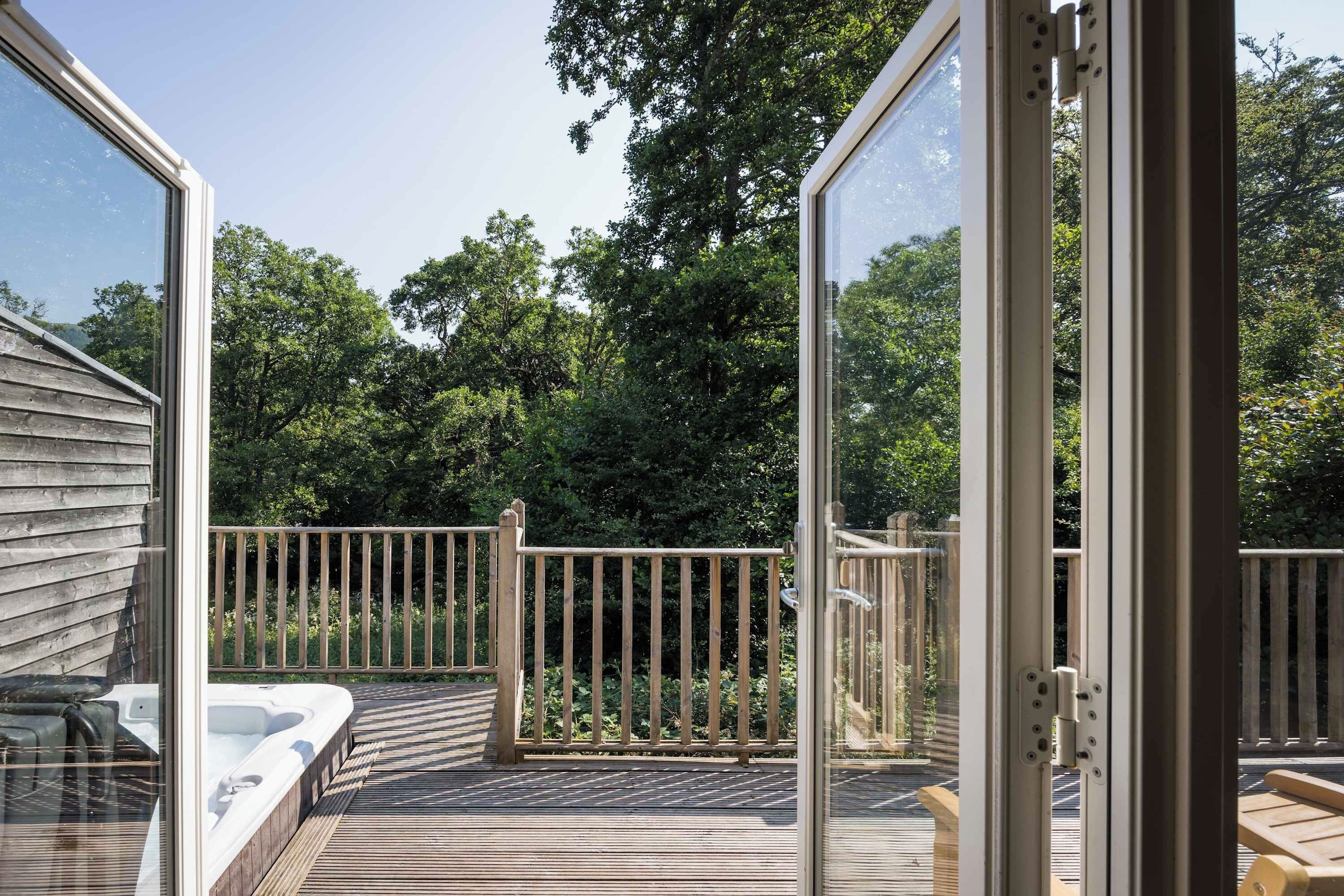 A wooden deck with a hot tub, surrounded by a wooden fence and trees.