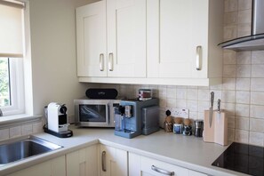 Eine Küche mit weißen Schränken, einer Kaffeemaschine, einer Mikrowelle, einem Toaster und einem Messerblock.