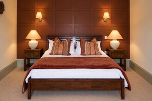 A hotel room with a large bed, two nightstands, two wall-mounted lamps, and a patterned throw blanket.