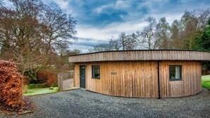 Eine Holzhütte mit gewölbtem Dach, einer Tür und zwei Fenstern.