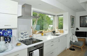 A modern kitchen with white cabinetry, a large window, and a built-in oven. - Osprey Boathouse Over Loch Tay with Hot Tub (Acharn)
