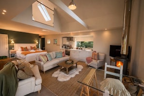 A spacious living area with a high ceiling, a sofa set, a coffee table, and a fireplace. - Osprey Boathouse Over Loch Tay with Hot Tub (Acharn)
