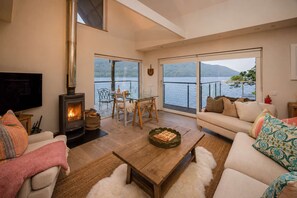 A cozy living room with a fireplace, a sofa, a coffee table, and a TV. - Osprey Boathouse Over Loch Tay with Hot Tub (Acharn)