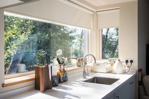 A modern kitchen with a large window, a sink, and a toaster. - Osprey Boathouse Over Loch Tay with Hot Tub (Acharn)