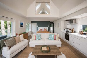 A modern interior with a living area, a bedroom with a large bed, and a kitchen. - Osprey Boathouse Over Loch Tay with Hot Tub (Acharn)