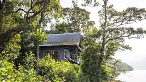 Una casa rodeada de vegetación exuberante, con vista al agua de fondo.