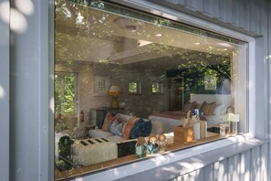 Una habitación con un ventanal grande, un sofá, una lámpara y una mesita con adornos.