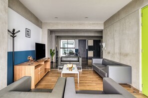 Un salon moderne avec un téléviseur à écran plat, un meuble de rangement en bois, des canapés gris et une table basse.