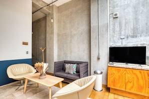 Un espace de vie moderne comprenant un canapé, des fauteuils, une petite table et un téléviseur.