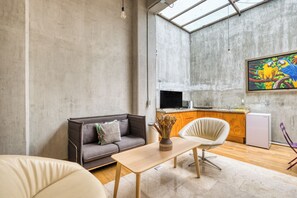 Een moderne woonruimte met een bank, een eettafel en een keuken voorzien van een koelkast en een televisie.