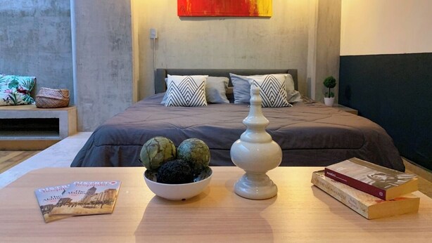 Ein modernes Schlafzimmer mit einem großen Bett, einer dekorativen Schale und Büchern auf einem Holztisch.