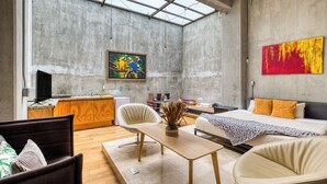 Un intérieur moderne avec une grande verrière, un lit, un bureau et un tableau accroché au mur.