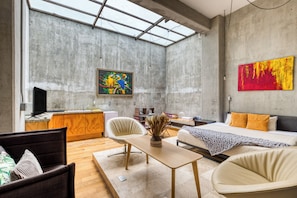 Ein modernes Interieur mit einem großen Oberlicht, einem Bett, einem Schreibtisch und einem Gemälde an der Wand.