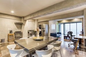 Une cuisine moderne dotée d’un grand îlot central, d’appareils électroménagers intégrés et d’un coin repas avec une grande table et des chaises.