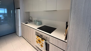 Cozinha moderna com forno embutido, pia e geladeira.