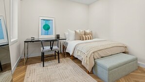 Une chambre à coucher avec un lit, un bureau, une chaise et un banc.