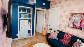 A living room with a blue sofa, a white coffee table, and a patterned rug. There is a kitchen area with a microwave and a refrigerator. - The Duo Suite 2 King Bedrooms Suite, Pool, Hot Tub (Palm Springs)