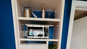 Une petite cuisine équipée comprenant un four à micro-ondes, un petit réfrigérateur et une étagère avec une plante et un verre.