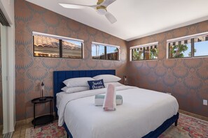 Une chambre à coucher avec un grand lit, un ventilateur de plafond et un papier peint à motifs.