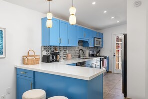 A modern kitchen with blue cabinets, a white countertop, and pendant lighting. - The Duo Suite 2 King Bedrooms Suite, Pool, Hot Tub (Palm Springs)