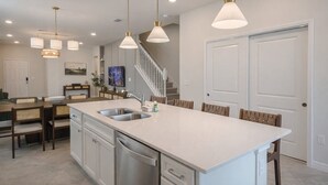 Una cucina moderna con un'isola grande, elettrodomestici in acciaio inossidabile e illuminazione a sospensione.