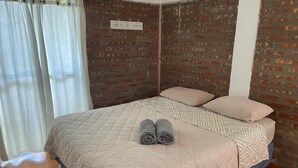 A neatly made bed with a quilted cover, two rolled towels, and a patterned pillow. - Los Colibríes duplex for rent (pet friendly) (Chubut)