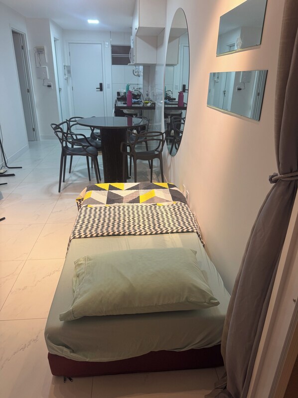 A small, neatly arranged bedroom with a bed, a table, and chairs. - Apartamento Praia de Iracema (Fortaleza)