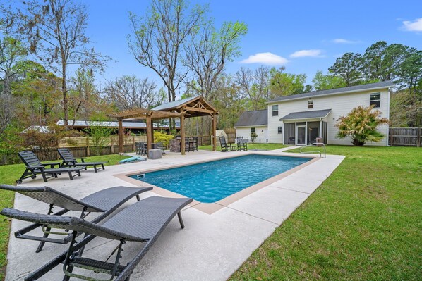 A backyard with a swimming pool, lounge chairs, a pergola, and a house. - Sleeps 10 - Private Pool - Close to Folly & Kiawah (Johns Island)