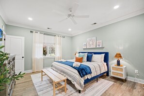 A bedroom with a bed, bedside table, bench, ceiling fan, window with curtains, and wall art. - Sleeps 10 - Private Pool - Close to Folly & Kiawah (Johns Island)