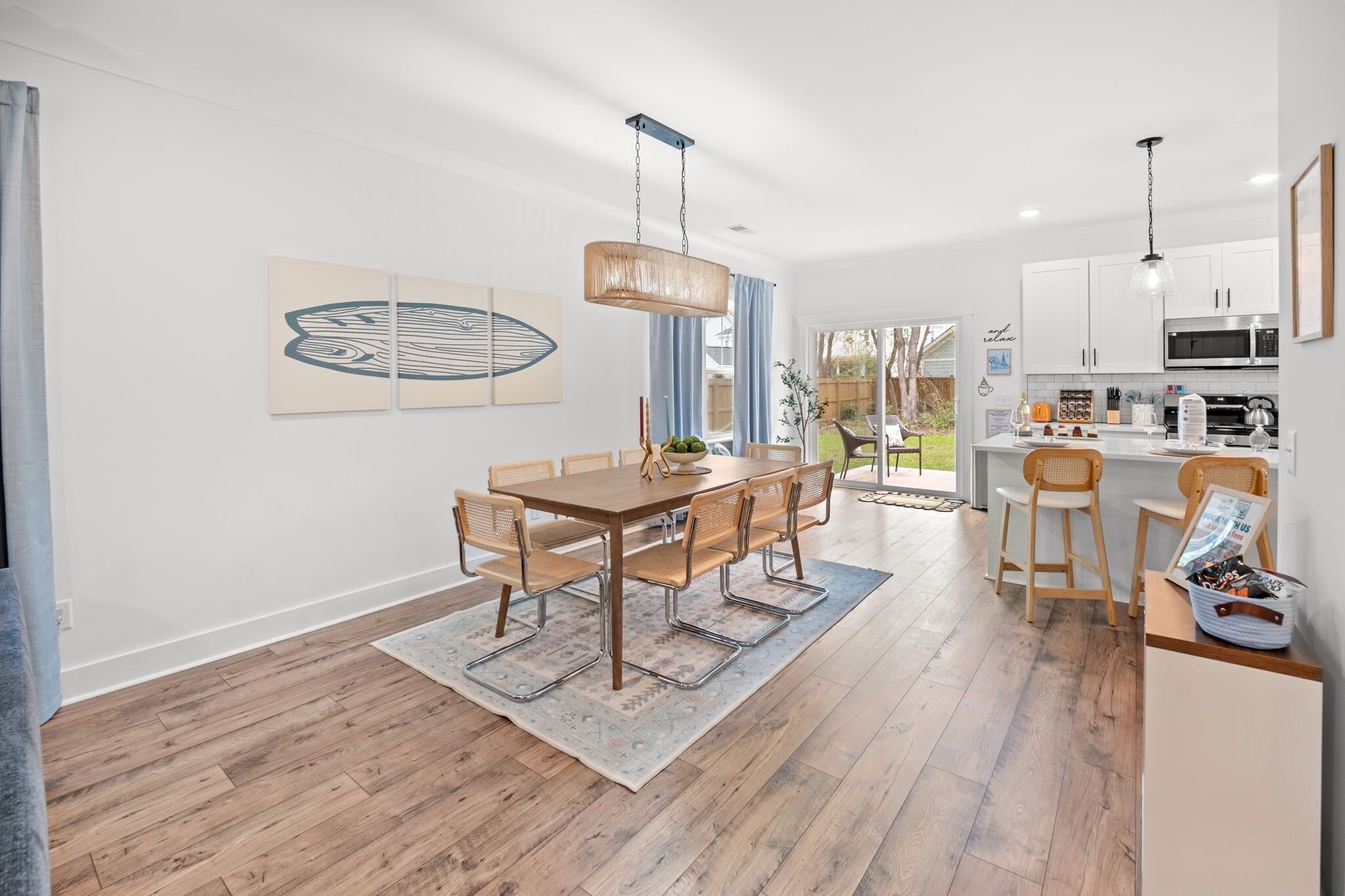 A modern kitchen with white cabinets, stainless steel appliances, and a dining area with a wooden table and chairs.