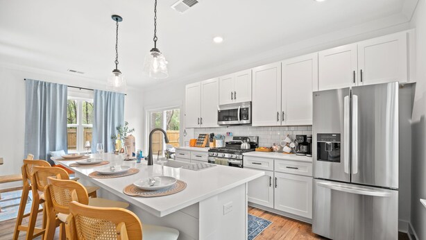 A modern kitchen with white cabinets, stainless steel appliances, and a central island with seating. - Close 2 DT & Beaches | 4 BR 10 Guests | Built 2025 (Charleston)