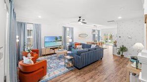 A modern living room with a sofa, chairs, a TV, and a wooden floor. - Close 2 DT & Beaches | 4 BR 10 Guests | Built 2025 (Charleston)