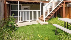 Ein zweistöckiges Haus mit Balkon, Treppe und einem Rasenstück.
