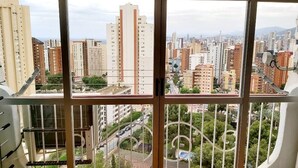 Vistes des d'un edifici alt amb diverses finestres, que mostren un paisatge urbà amb diferents edificis i una carretera a sota.