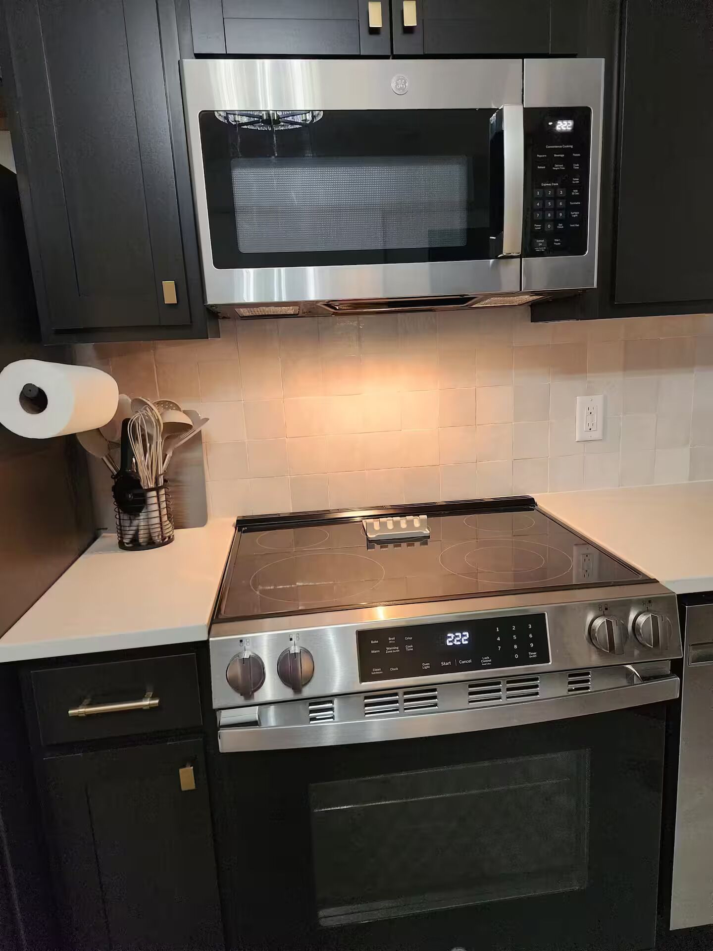 Een keuken met een roestvrijstalen magnetron, oven en kookplaat.