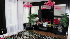 Ein modernes Wohnzimmer mit Schwarz-Weiß-Dekor, einem Glastisch und zwei schwarzen Sofas mit gemusterten Kissen.