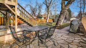 A patio with a round table and four chairs, surrounded by stone tiles.