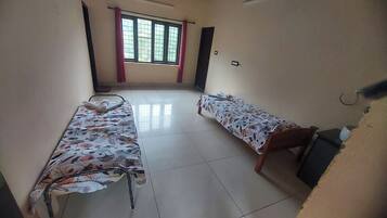 Un dormitorio con dos camas individuales, una ventana con cortinas y suelo de baldosas.