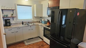 A compact kitchen with a black refrigerator, a microwave, a toaster, and a coffee maker.