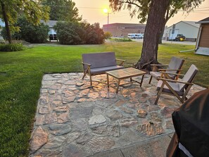 Un patio al aire libre con suelo de piedra, una mesa de madera y dos sillas.