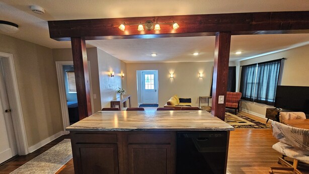 A spacious kitchen with a central island, wooden cabinets, and a built-in dishwasher.