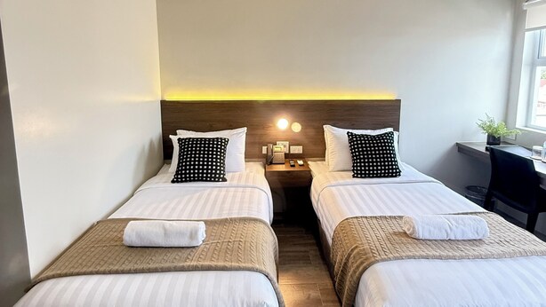 A hotel room with two single beds, a desk, and a chair. - Mango Suites Angeles (Angeles City)