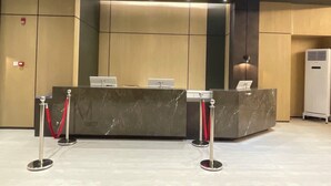 A reception desk with two computers, a red rope barrier, and an air conditioning unit. - Mango Suites Angeles (Angeles City)