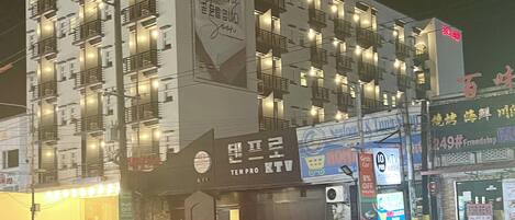 A multi-story hotel with balconies, a large illuminated sign, and various commercial establishments on the ground floor.