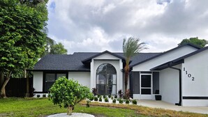 Une maison moderne à l’extérieur blanc, dotée d’un garage et d’une pelouse bien entretenue avec un petit arbre.