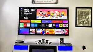 Un téléviseur fixé au mur affiche une offre spéciale pour le « Black Friday » et propose diverses applications de diffusion en continu.