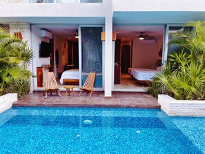 Ein modernes Hotel mit Schwimmbad, zwei Schlafzimmern und einer Sitzecke mit Holzsesseln und einem Tisch.